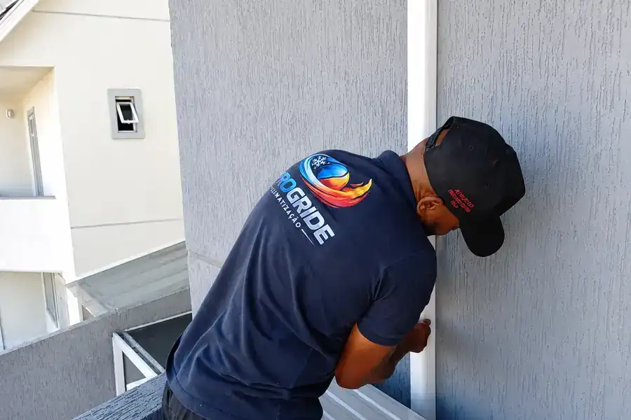 Técnico da Progride instalando a condensadora na varanda de um apartamento